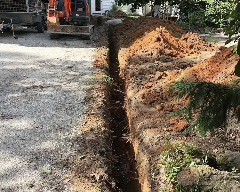 A trench is being excavated in front of a house.