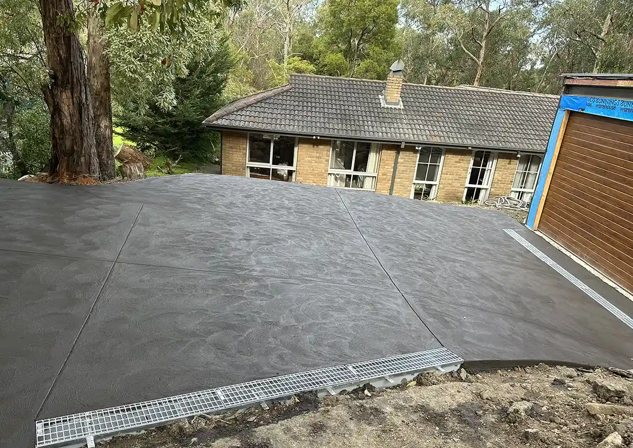 A new coloured concrete driveway leading up to a garage | DigKing