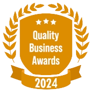 A golden shield with a laurel wreath and banner, displaying "Quality Business Awards 2024" with three stars at the top.